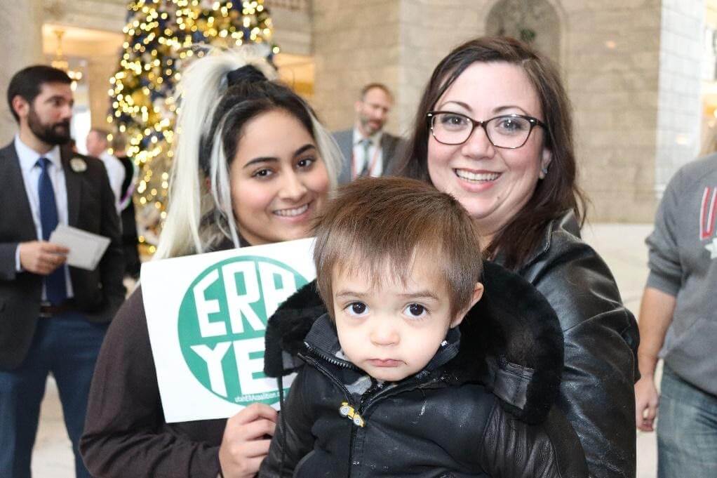 Teen girl, toddler and mom holding ERA YES sign