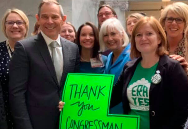 Several women surrounding Congressman Curtis with ERA sign